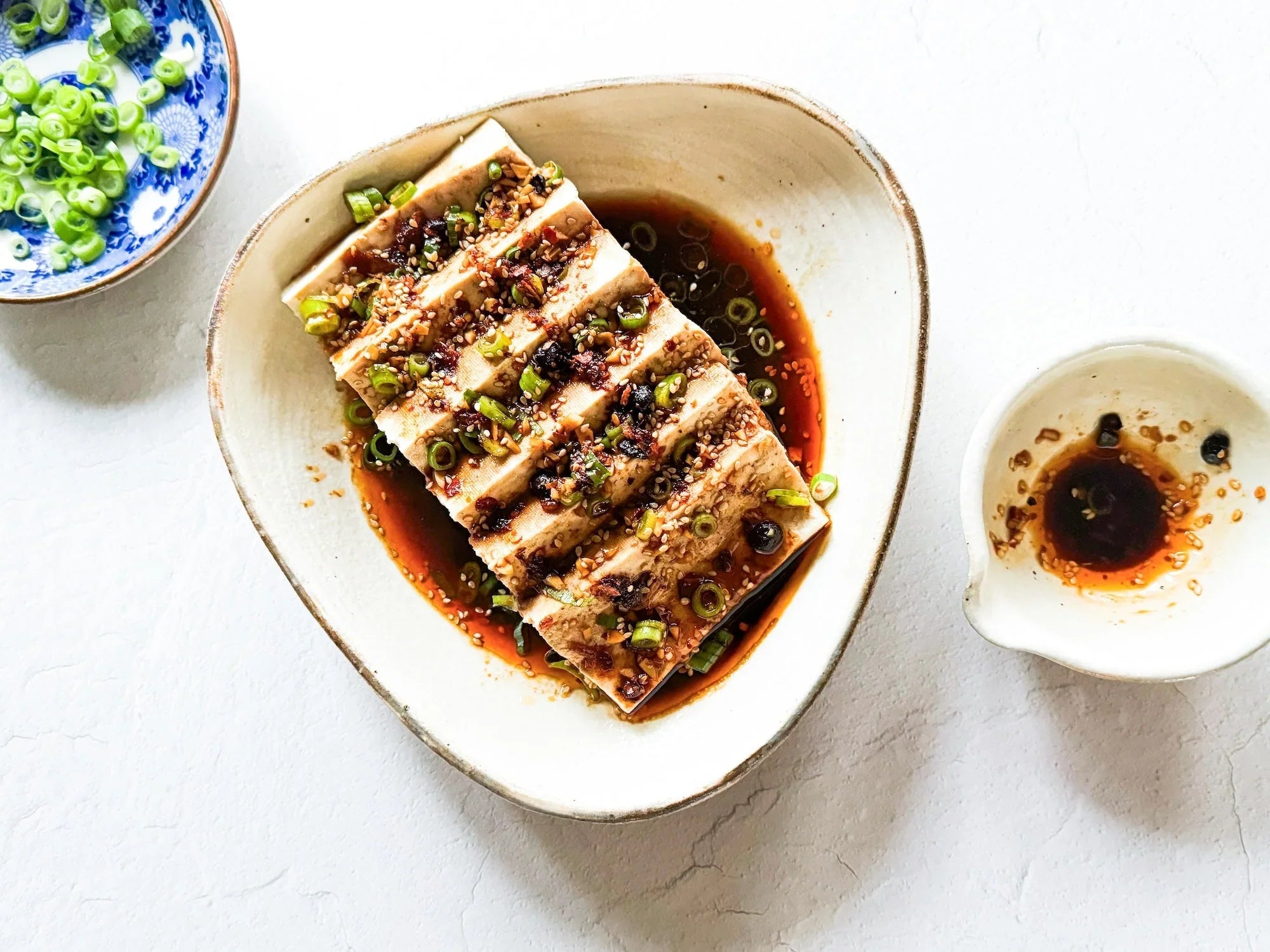 Steamed tofu with soy sauce, black vinegar, garlic, scallions, sesame seeds, and optional chili oil.