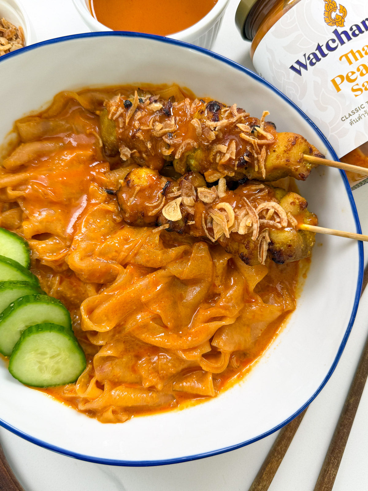 Thai peanut sauce rice paper noodles topped with chicken satay skewers, fresh herbs, and crushed peanuts in a bowl – quick Thai-inspired dinner.