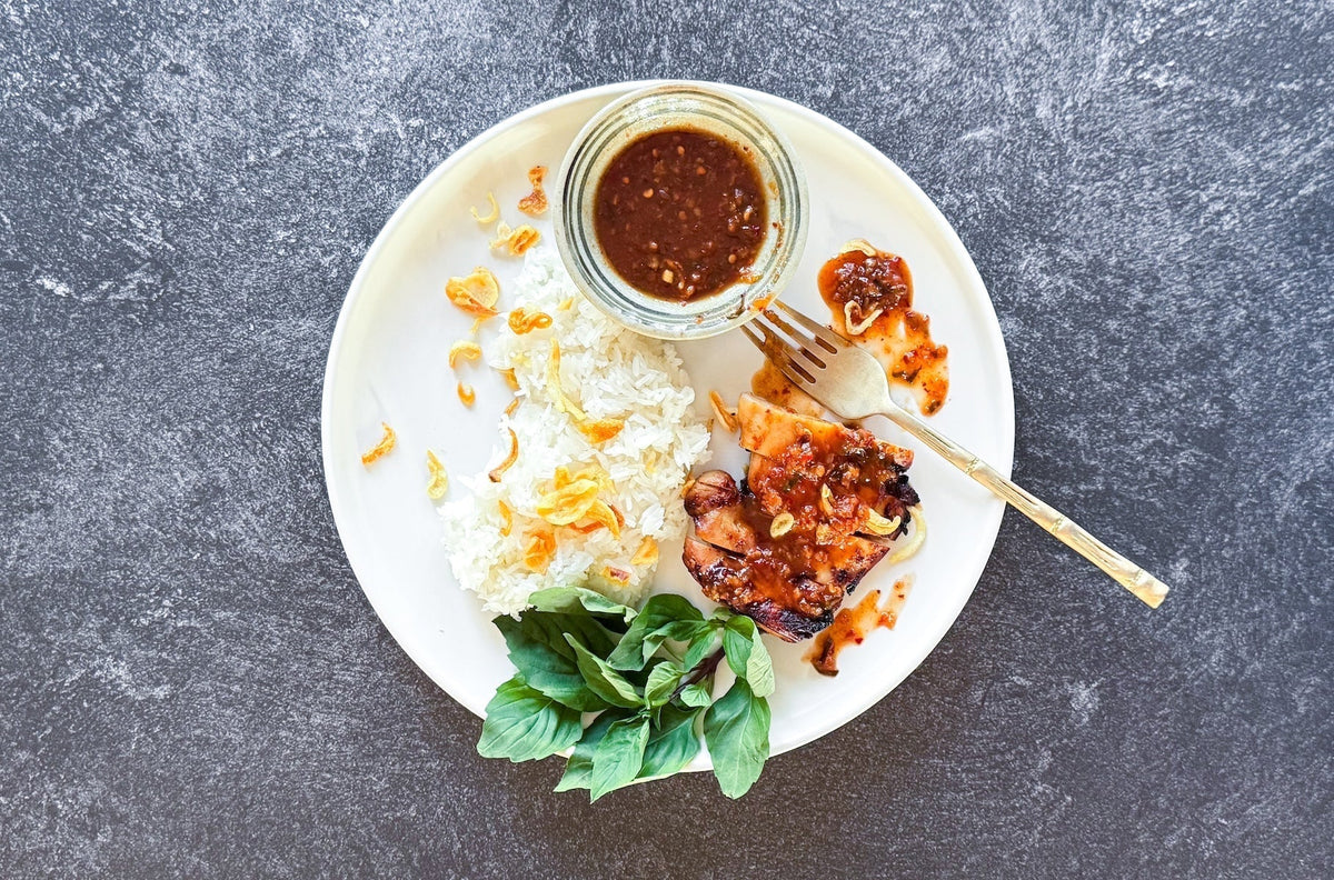 Sriracha Chicken with Sticky Rice plated with fresh Thai herbs and jasmine rice