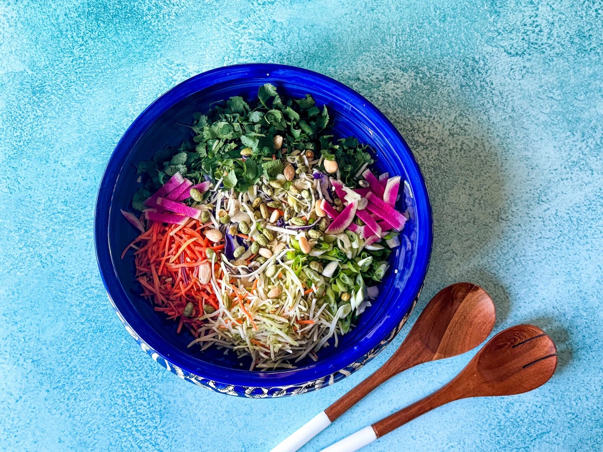Colourful Asian slaw in a bowl with shredded cabbage, carrots, and peanut sauce drizzle