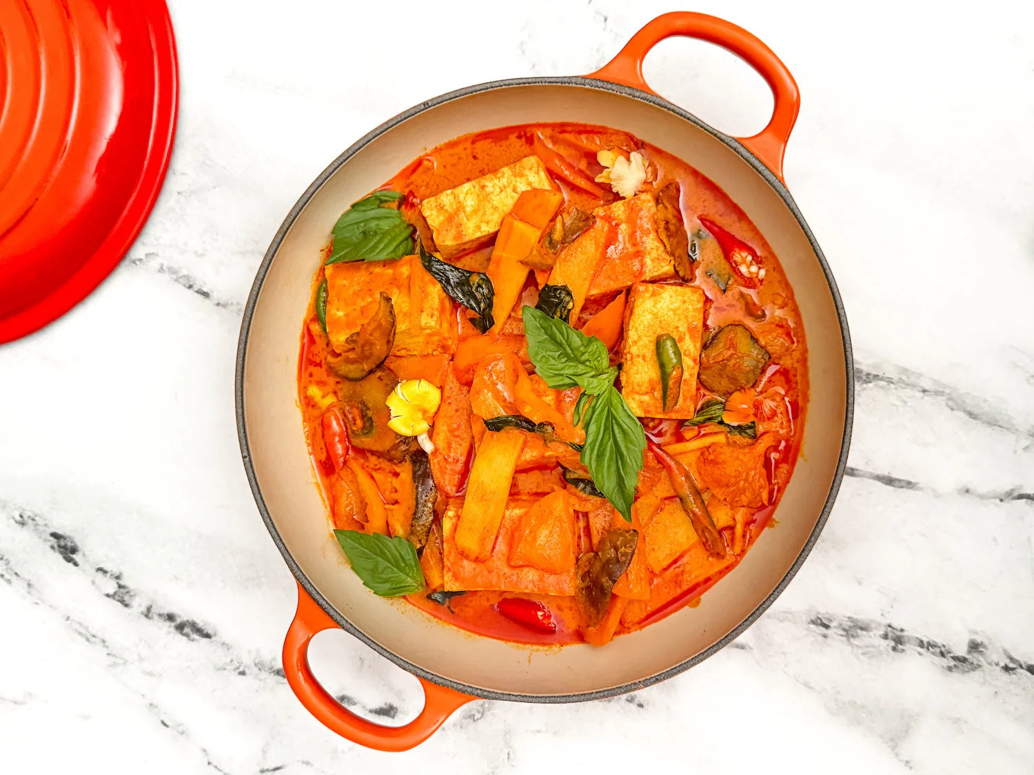 Vegan Thai red curry with golden tofu, mushrooms, and bamboo shoots in a dark clay bowl