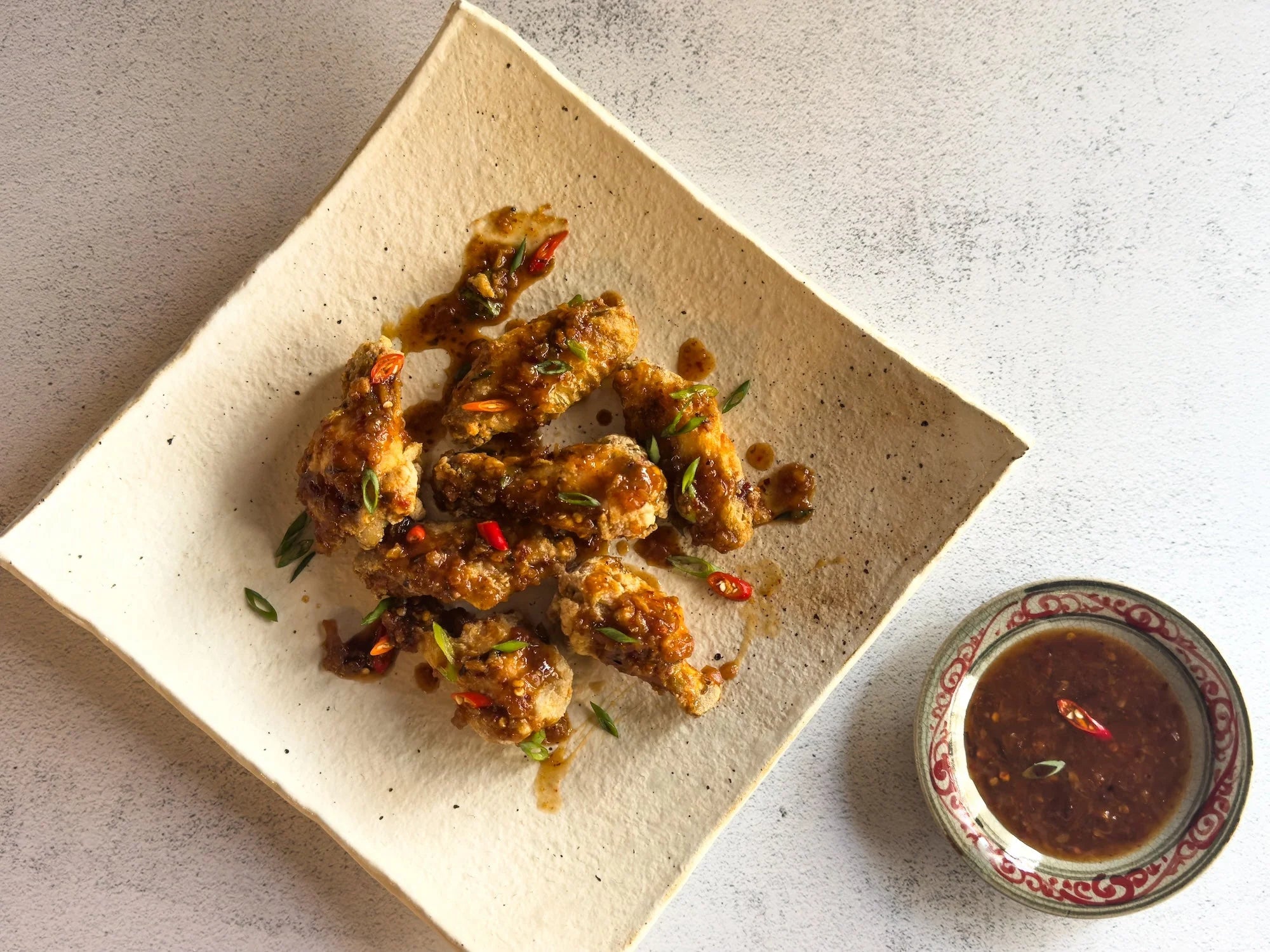 Crispy Chicken Wings with Award-Winning Thai Spicy Chili Sauce plated with fresh Thai herbs and jasmine rice