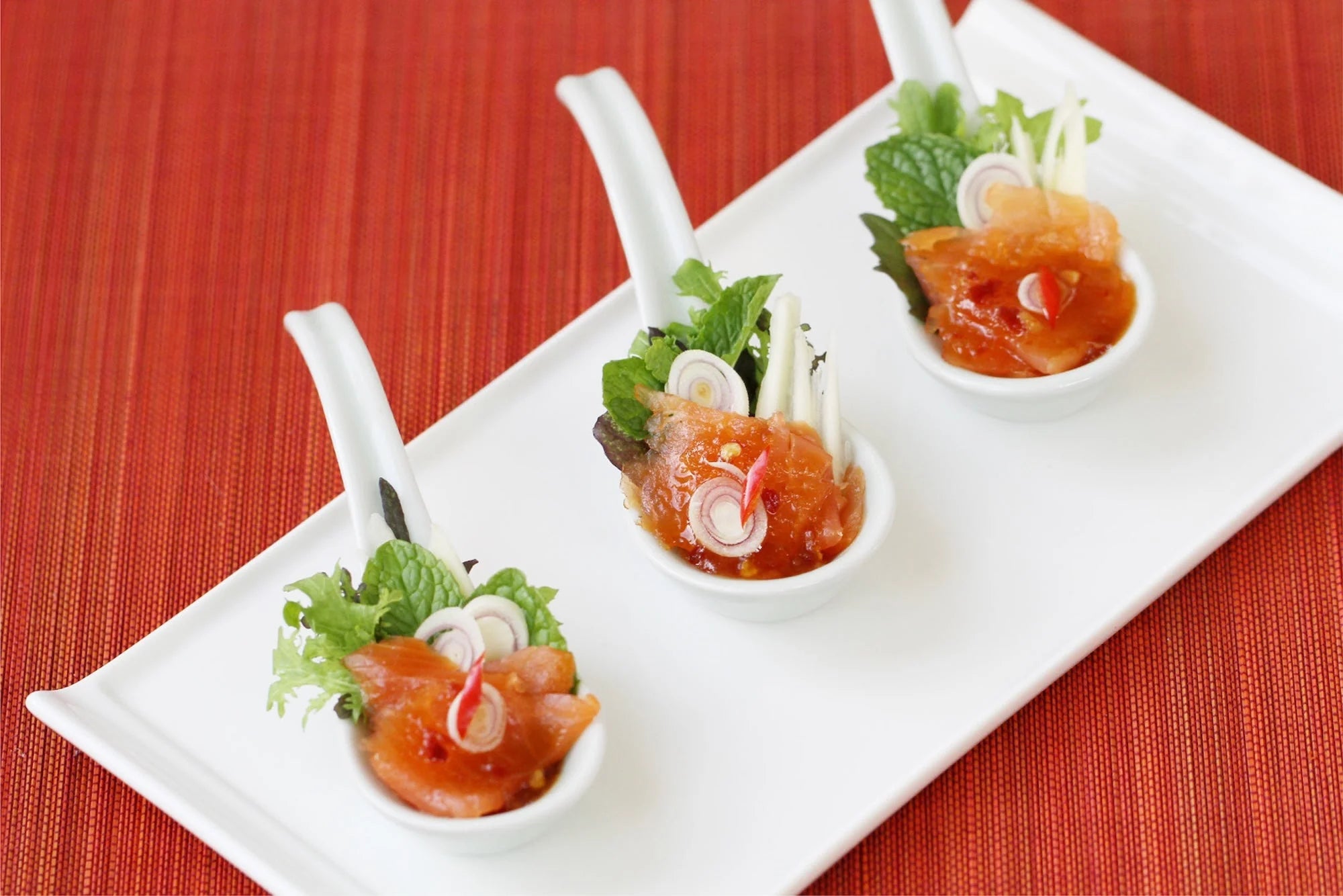 Plated smoked salmon salad with avocado, greens, and a drizzle of pad thai sauce