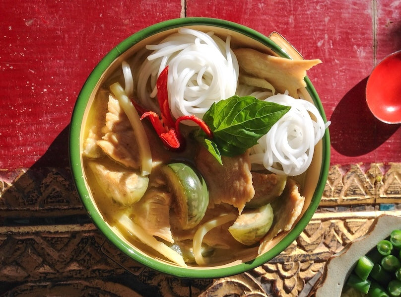 Thai green curry chicken with noodles, eggplant, and basil in a creamy coconut curry sauce